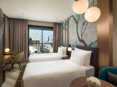 Moderní hotelový pokoj se dvěma jednolůžky, výhledem na město a stylovým zařízením.