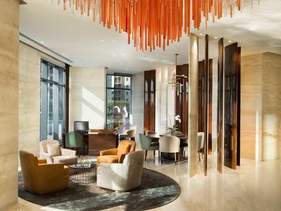 Elegantní hotelový salonek s pohodlnými křesly a moderním stropním osvětlením.