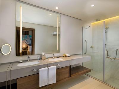 Bagno moderno con grande specchio, doppi lavandini e doccia in vetro.