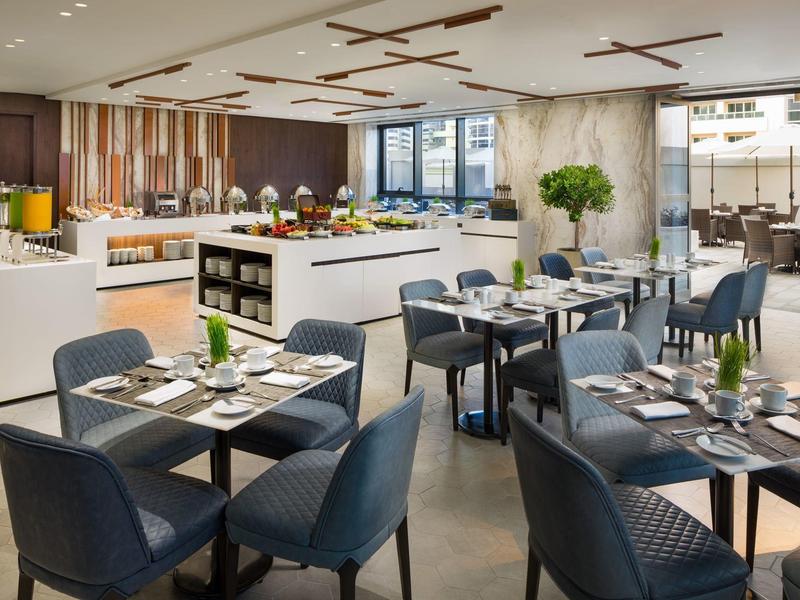 Moderní hotelová jídelna s prostřenými stoly a samoobslužným bufetem.