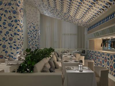 Elegantes Restaurant mit blauer floraler Tapete und gedeckten Tischen in warmem Licht.