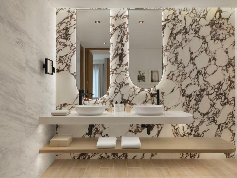 Nowoczesna łazienka z dwoma umywalkami i ozdobną ścianą marmurową.