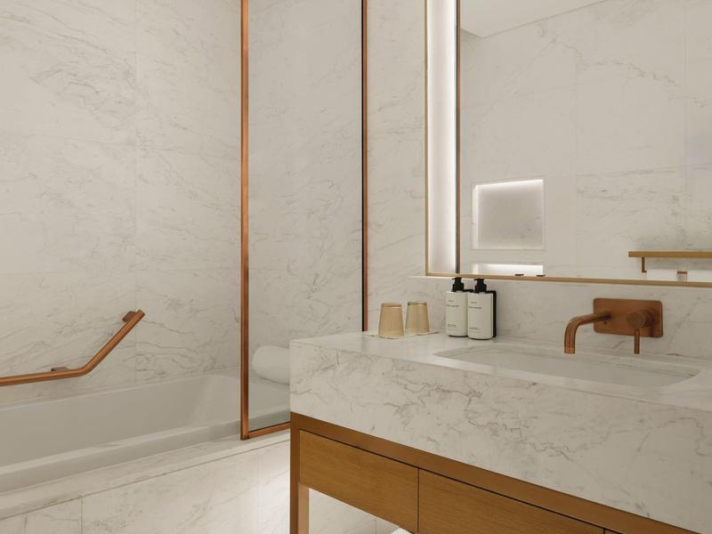 Nowoczesna łazienka z marmurowymi ścianami, drewnianymi akcentami i podświetlanym lustrem.