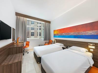 Moderne hotelkamer met twee eenpersoonsbedden, bureau en groot raam met uitzicht op de stad.