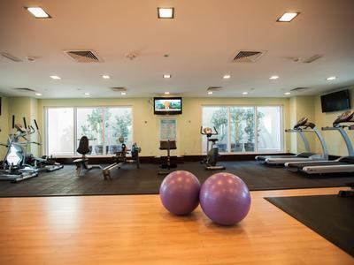 Bright gym with exercise equipment, two fitness balls, and two people with a tablet.