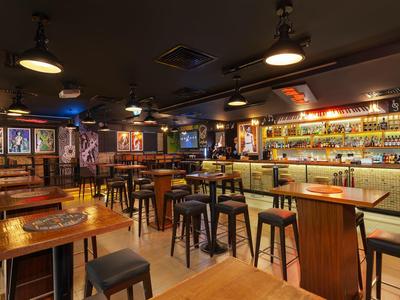 Gezellige bar met houten tafels, krukken en verlichte bar in een warme sfeer.