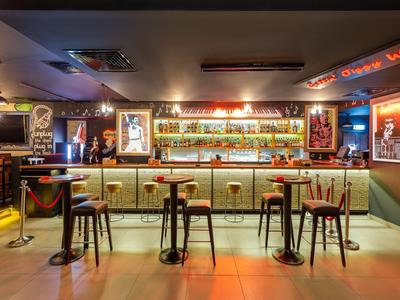 Modern hotel bar with illuminated counter, high stools, and trendy atmosphere.