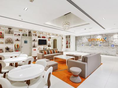 Modern, bright hotel lobby with white furniture and orange carpet.