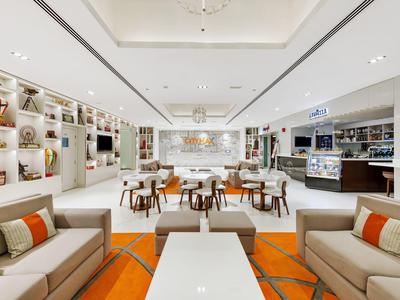 Lichte, moderne hotel-lounge met sofa's, fauteuils, tafels en decoratieve wandverlichting.