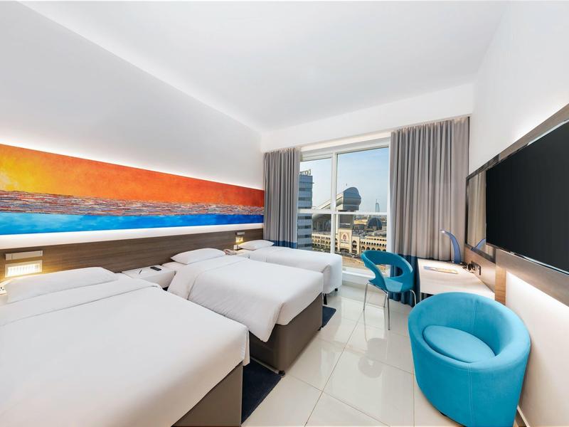 Moderne hotelkamer met twee eenpersoonsbedden, zeezicht en blauwe fauteuils.