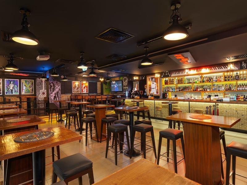 Gezellige bar met houten tafels, krukken en verlichte bar in een warme sfeer.