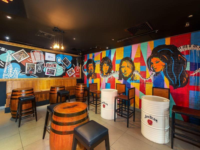 Kleurrijke bar met muurschildering, houten tafels en stoelen, artistiek ingericht.