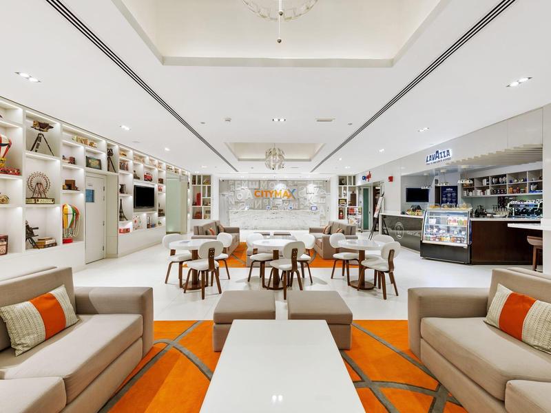 Lichte, moderne hotel-lounge met sofa's, fauteuils, tafels en decoratieve wandverlichting.