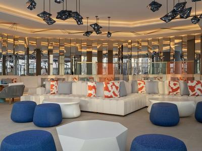 Hall d'hôtel moderne avec des coins salon confortables et des coussins décoratifs sous un éclairage chaleureux.