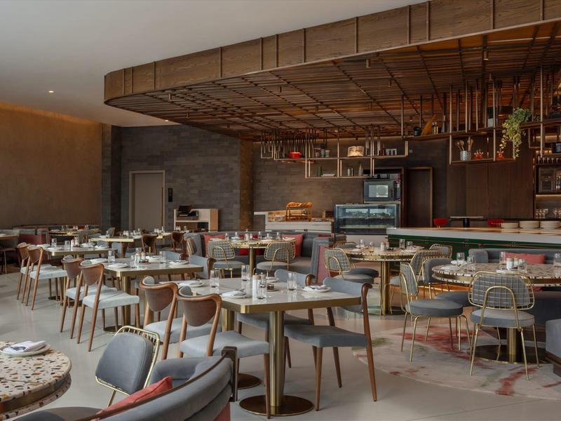 Espace restaurant moderne avec tables dressées et plafond en bois au design élégant.