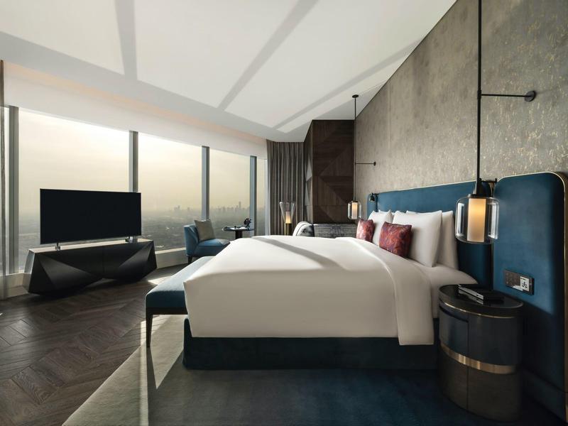 Chambre d'hôtel moderne avec deux lits, grande fenêtre et télévision sur sol gris foncé