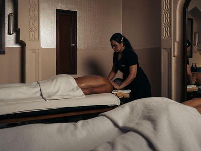 Kobieta otrzymuje masaż w spokojnym, słabo oświetlonym pokoju spa.