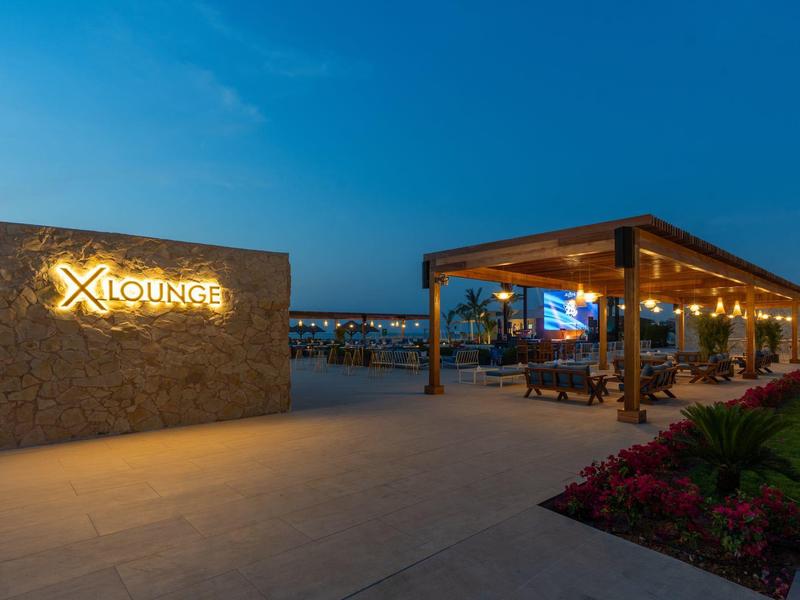 Beleuchteter Außenbereich eines Hotels mit Lounge und Sitzecke bei Dämmerung.