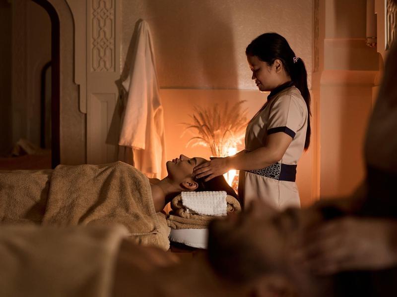 Eine Frau wäscht einer anderen Frau im warm beleuchteten Raum die Haare.