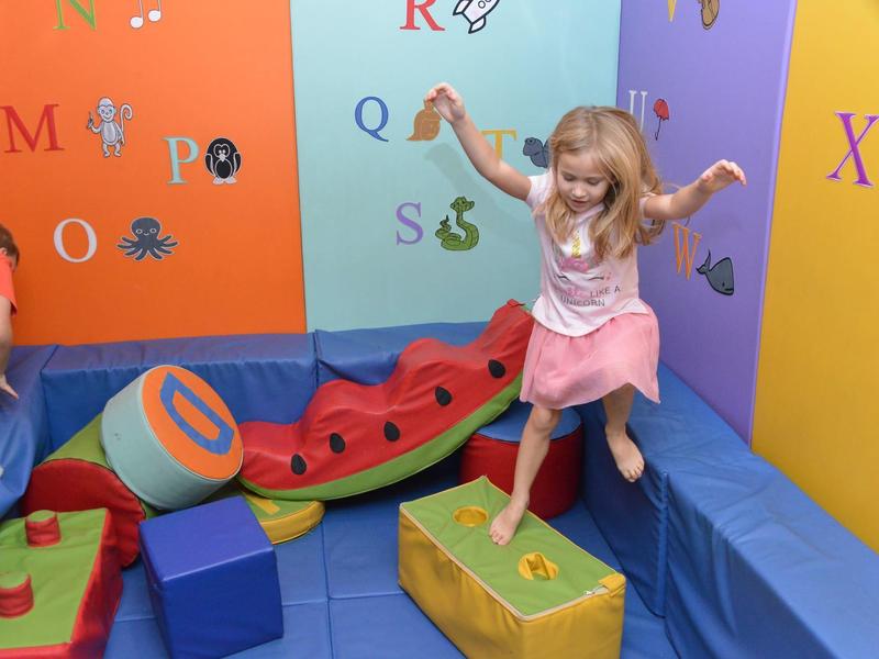 Kinder spielen in einem bunten Raum mit weichen Kletter- und Balancierspielen aus Schaumstoff.
