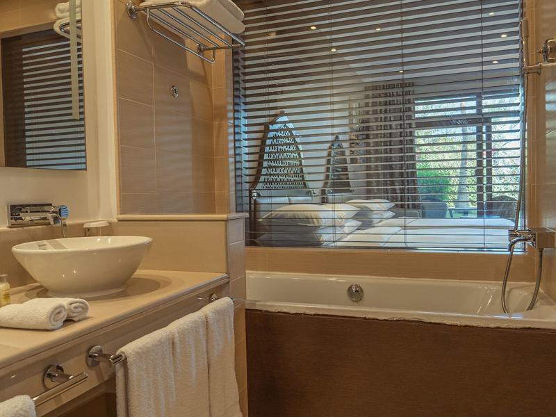 Modernes Badezimmer mit Waschbecken auf Holzplatte und Badewanne hinter Glaswand.