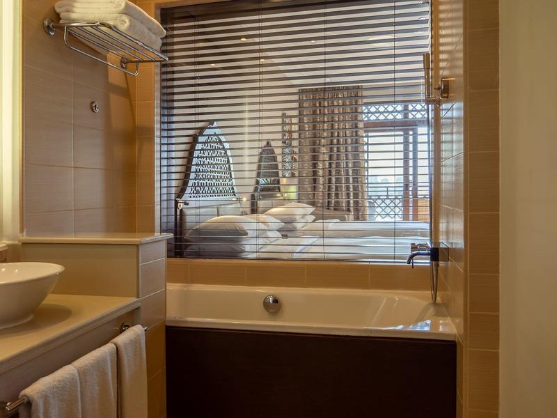 Gemütliches Badezimmer mit Waschbecken, Handtüchern und Badewanne neben einem Fenster mit Jalousien.