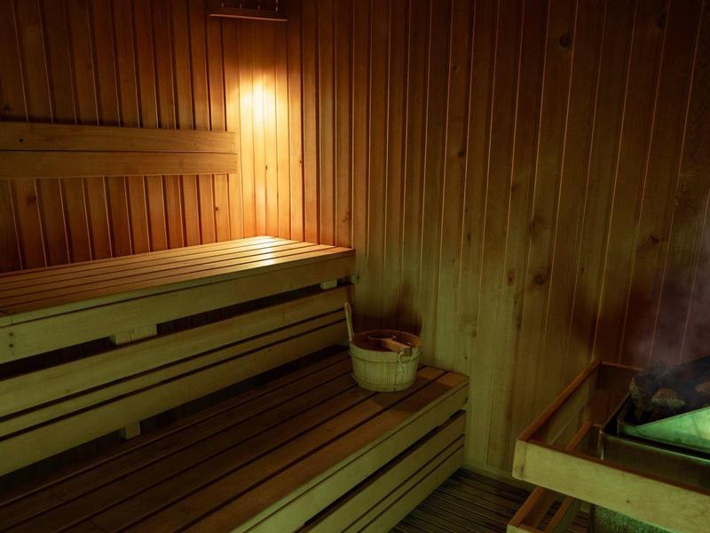 Innenraum einer Sauna mit Holzverkleidung, mehrstufigen Bänken und gedämpftem Licht.