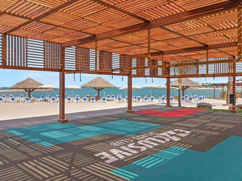 Überdachte Lounge am Strand mit Liegestühlen und Blick auf die Sonne und das Meer.