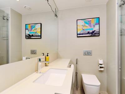 Moderní hotelová koupelna s velkým zrcadlem, umyvadlem a toaletou.