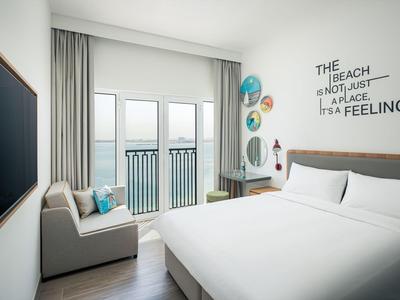 Helles Hotelzimmer mit Doppelbett, Sofa, Balkon und Meerblick.