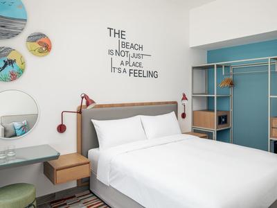 Moderní hotelový pokoj s manželskou postelí, nástěnnými policemi, zrcadlem a dekorací s nápisem na zdi.