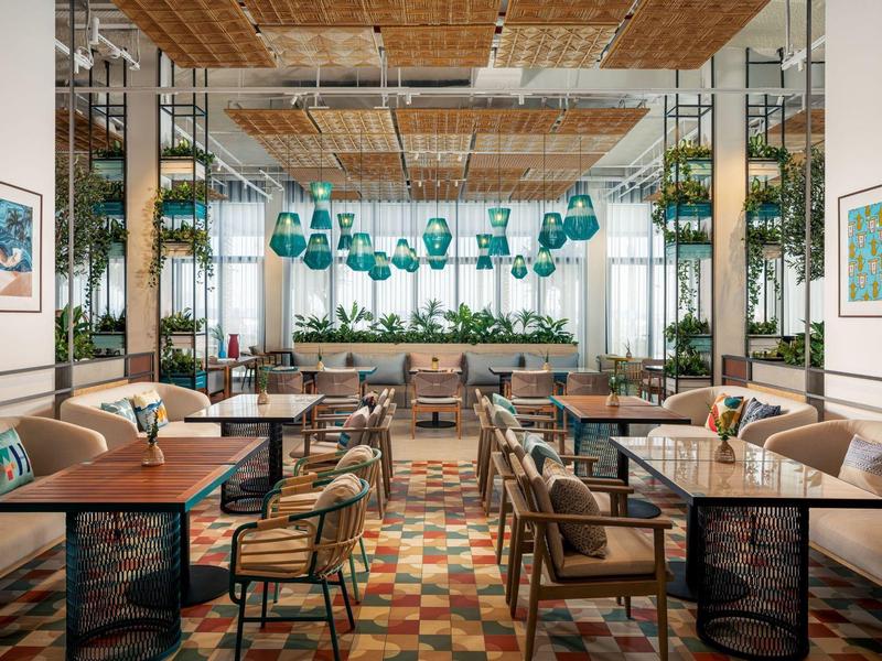 Moderně zařízená jídelna s dřevěnými stoly, čalouněnými židlemi a barevnou dlažbou.