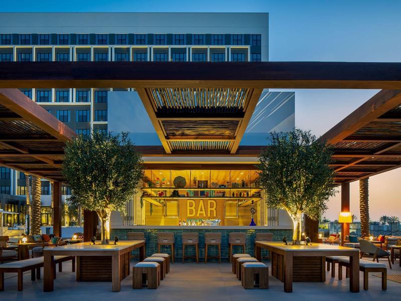 Moderní venkovní prostor s barem, dřevěnou pergolou a sezením při soumraku