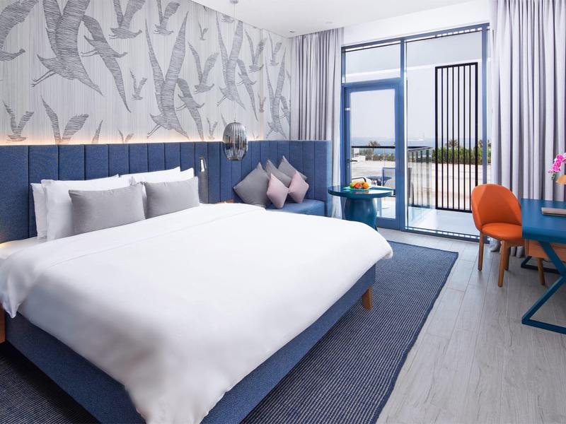 Modernes Hotelzimmer mit großem Bett, Blautönen und Balkon mit Aussicht.