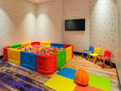 Colorful play area with ball pit, small basketball, and colorful child chairs in a hotel room.