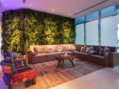 Gemütliche Sitzecke mit Ecksofa, bunt gemustertem Teppich und lebendiger grüner Pflanze an der Wand.