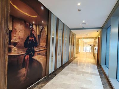 Pasillo de hotel moderno y luminoso con suelo de mármol y una gran obra de arte en la pared.