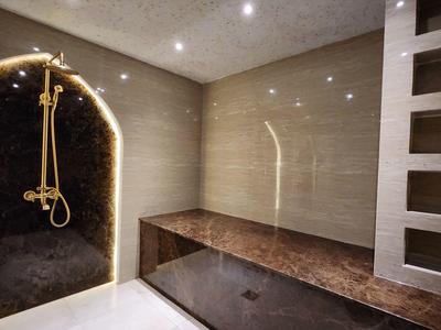 Ducha moderna con paredes de piedra y banco largo en un baño elegante y minimalista.