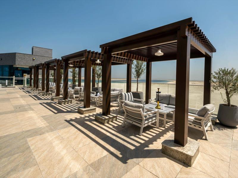 Terraza soleada con pérgolas, sillas y vista al mar en un hotel.