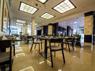 Modern hotel restaurant with stylish tables and chairs, illuminated by large ceiling lights.