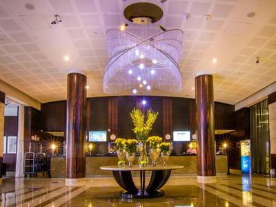 Luxurious hotel lobby with large floral centerpiece on round table and elegant lighting.