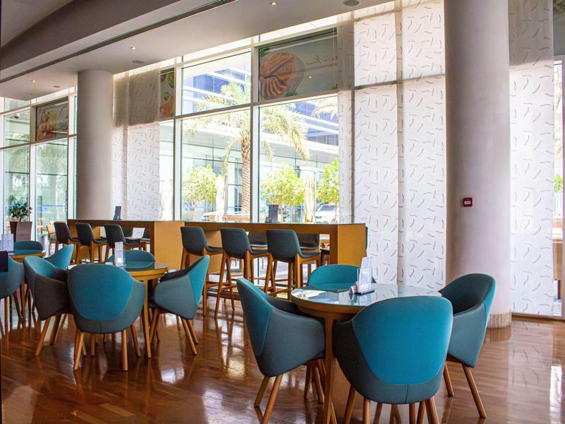 Modern hotel lounge area with blue chairs and large windows