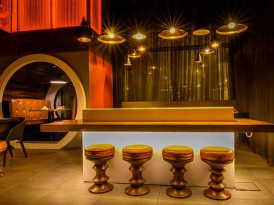 Nowoczesny bar z pięcioma okrągłymi stołkami barowymi i ciepłym oświetleniem.