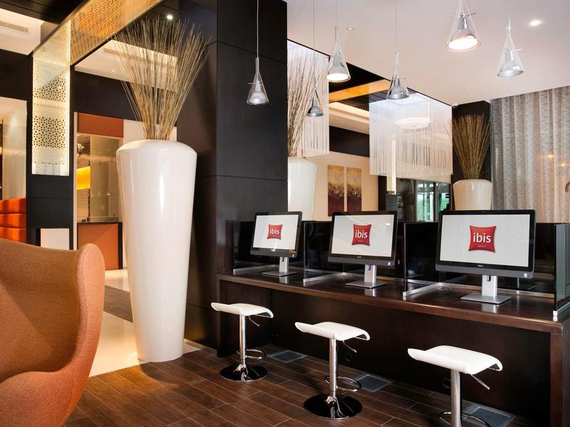 Modern hotel computer area with white stools and large vases in a warm ambiance.