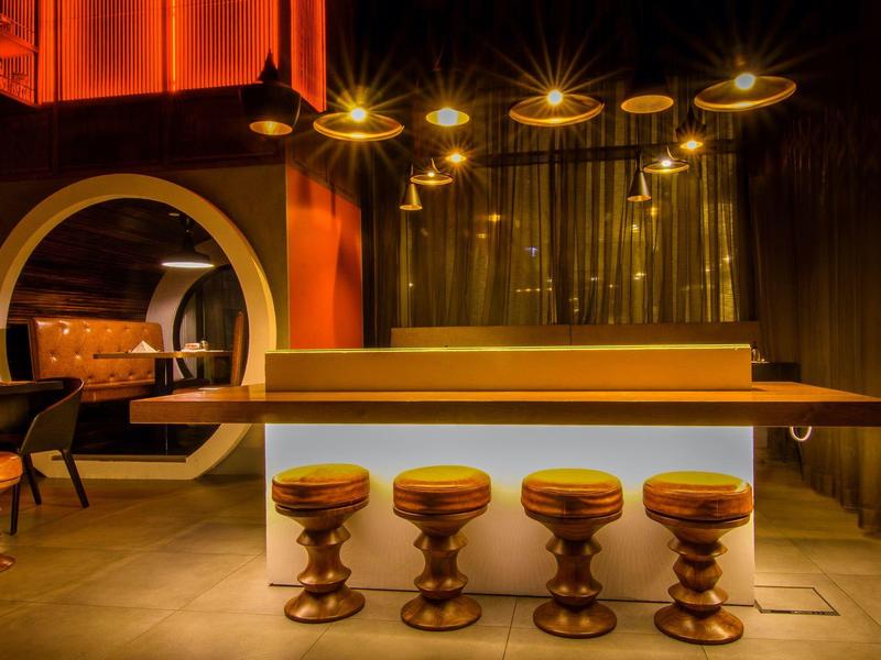 Modern bar with five stools and warm yellow lighting in a stylish interior.