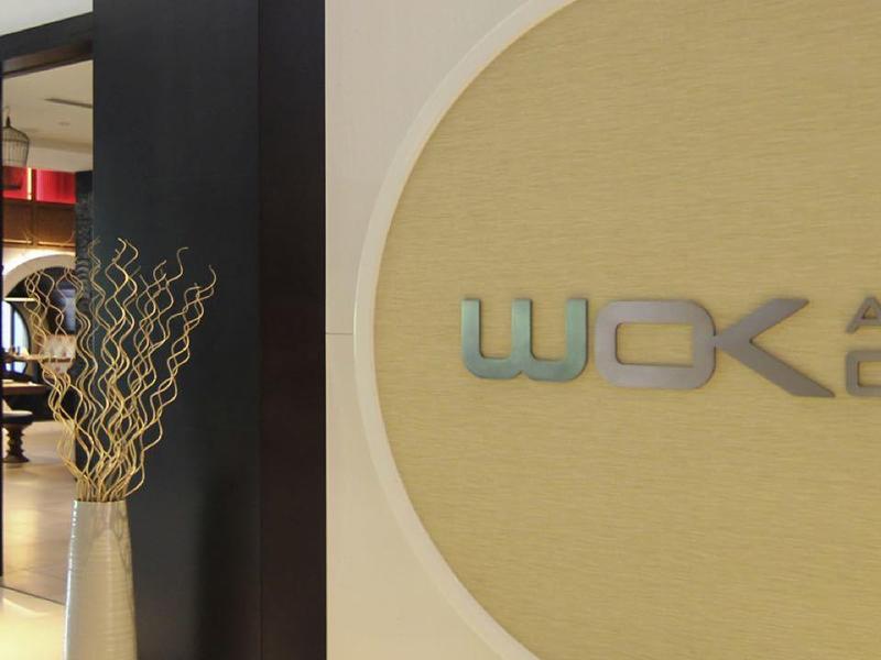 Modern reception area with WOK AND CO logo on the wall and decorative flower arrangement.