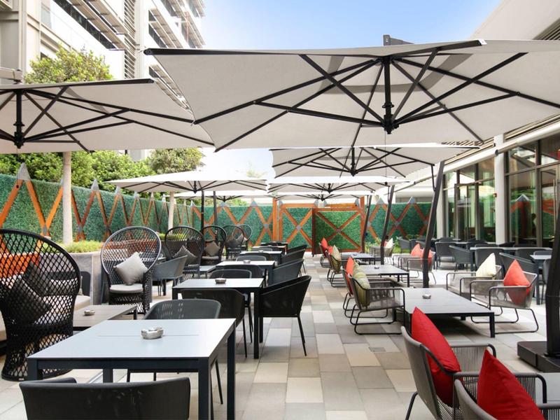 Modern hotel outdoor area with tables, chairs, and large umbrellas.