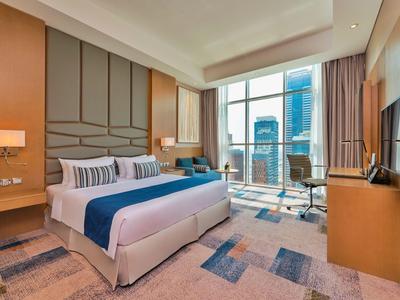 Camera d'hotel moderna con letto grande, scrivania e finestra con vista sulla città