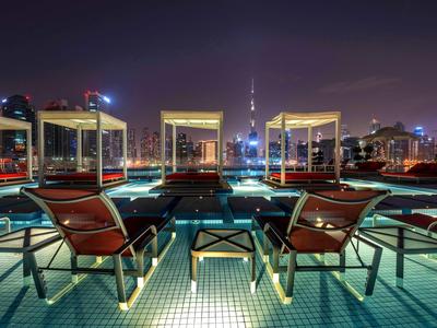 Terrazza illuminata con sedie a sdraio e vista sulla città di notte