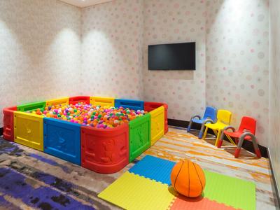 Colorful play area with balls, children's chairs, and basketball in a bright room.
